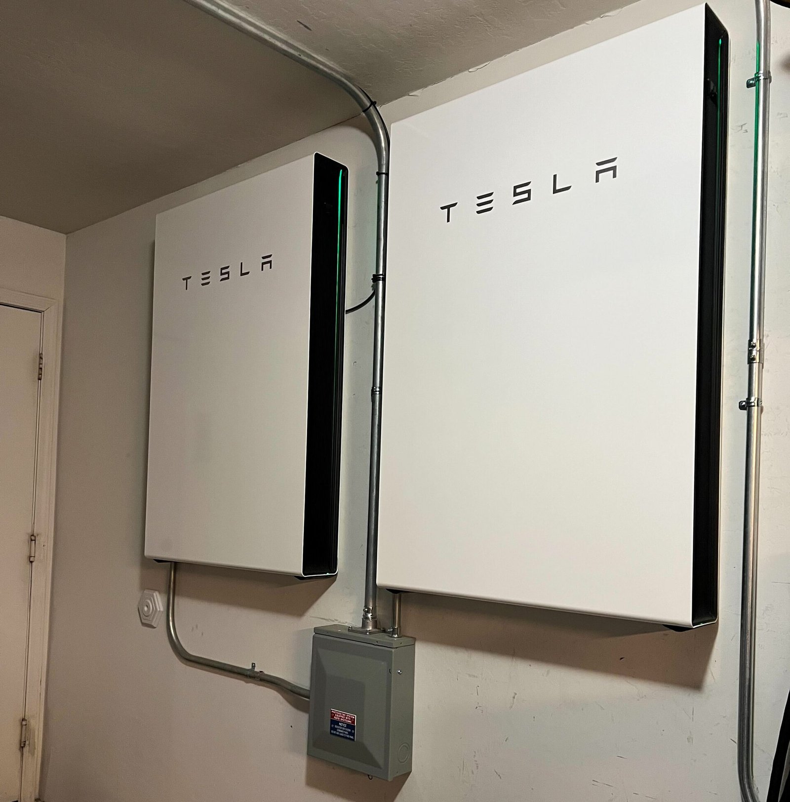 Deux batteries domestiques murales blanches installées dans le garage d'une maison