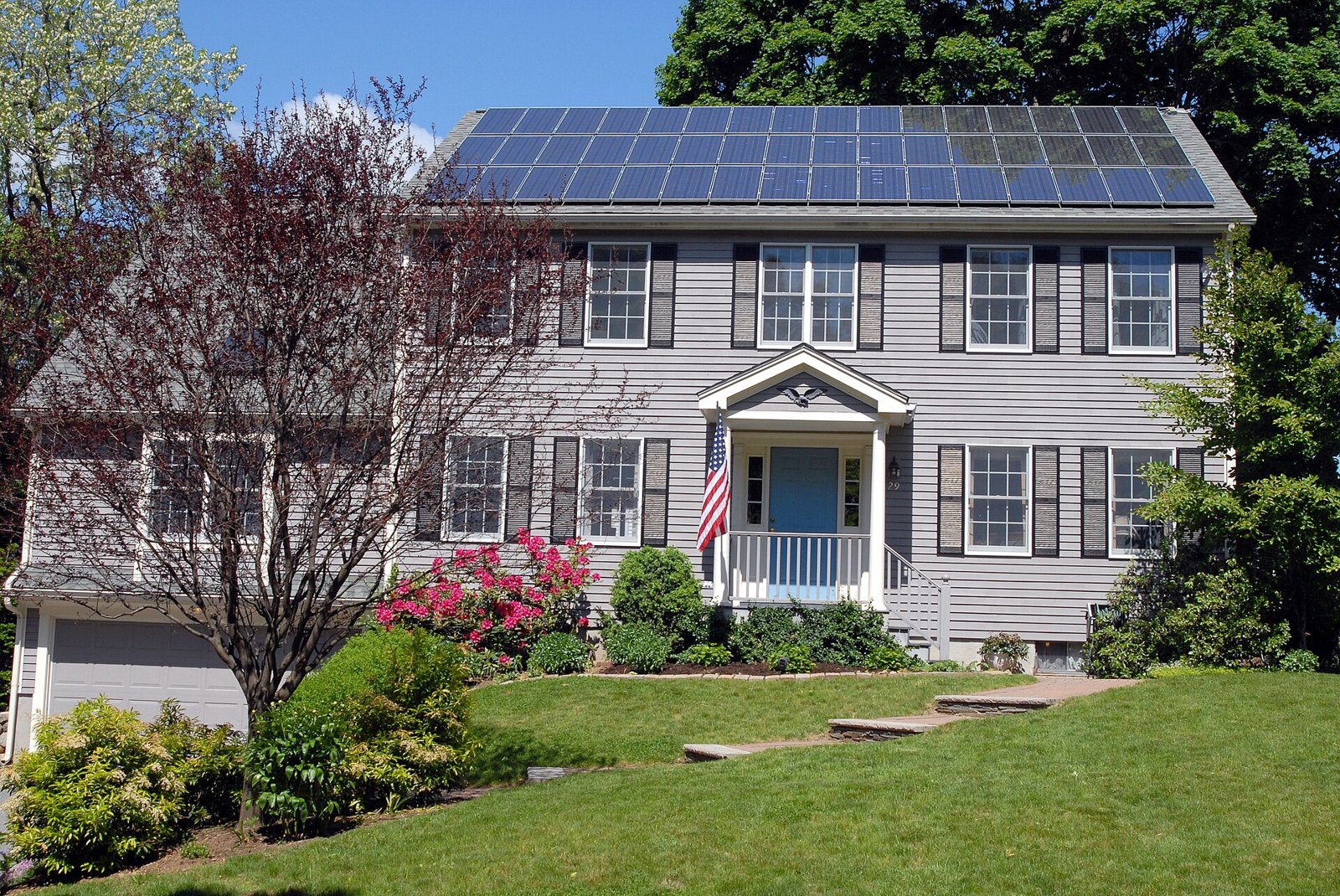 Maison individuelle dont le toit est équipé de panneaux solaires, entourée d'un jardin
