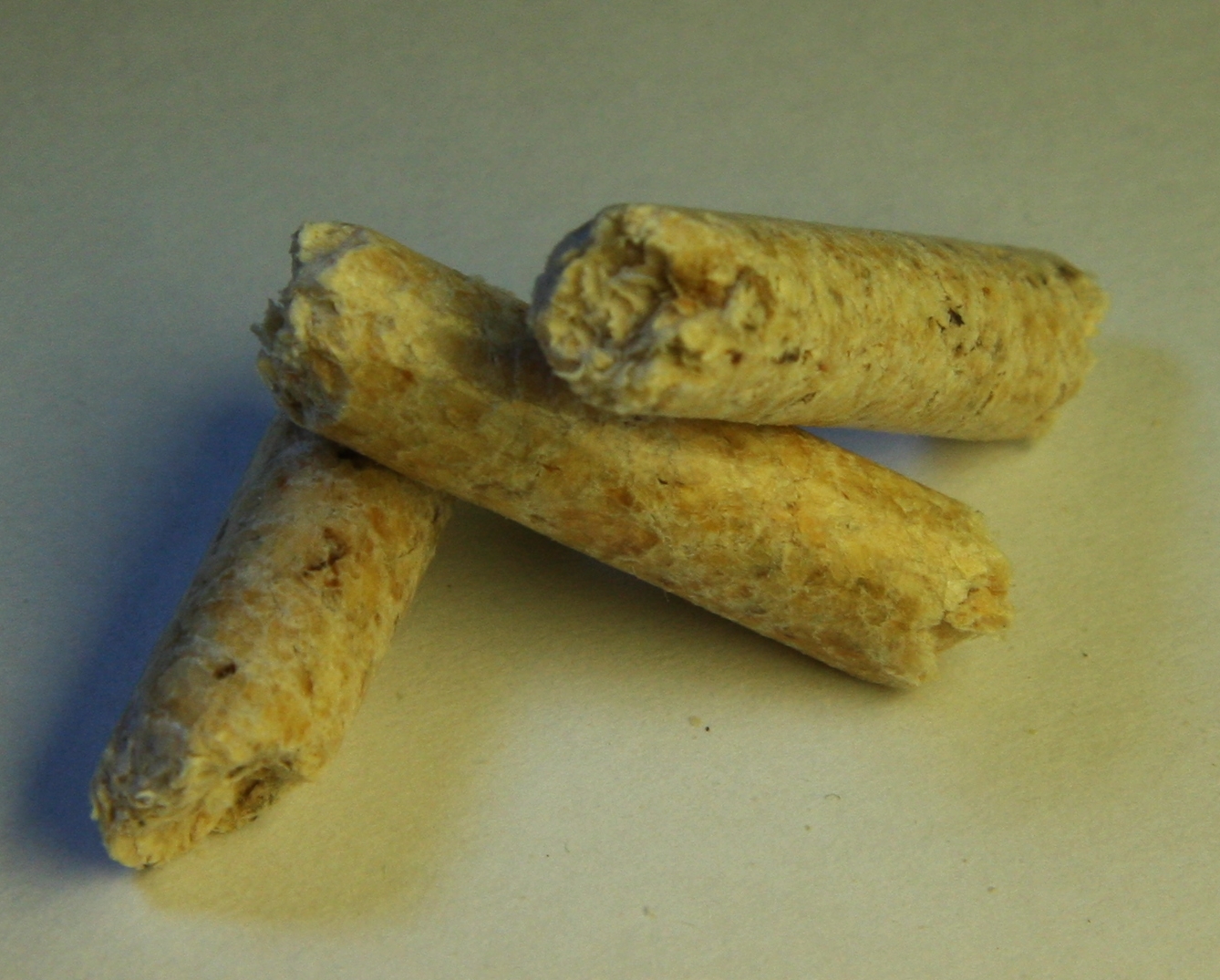 Trois granulés de bois (pellets) vus de près